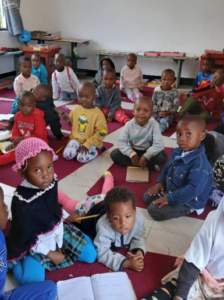 pictures of children sitting on mats in classroom in Arusha